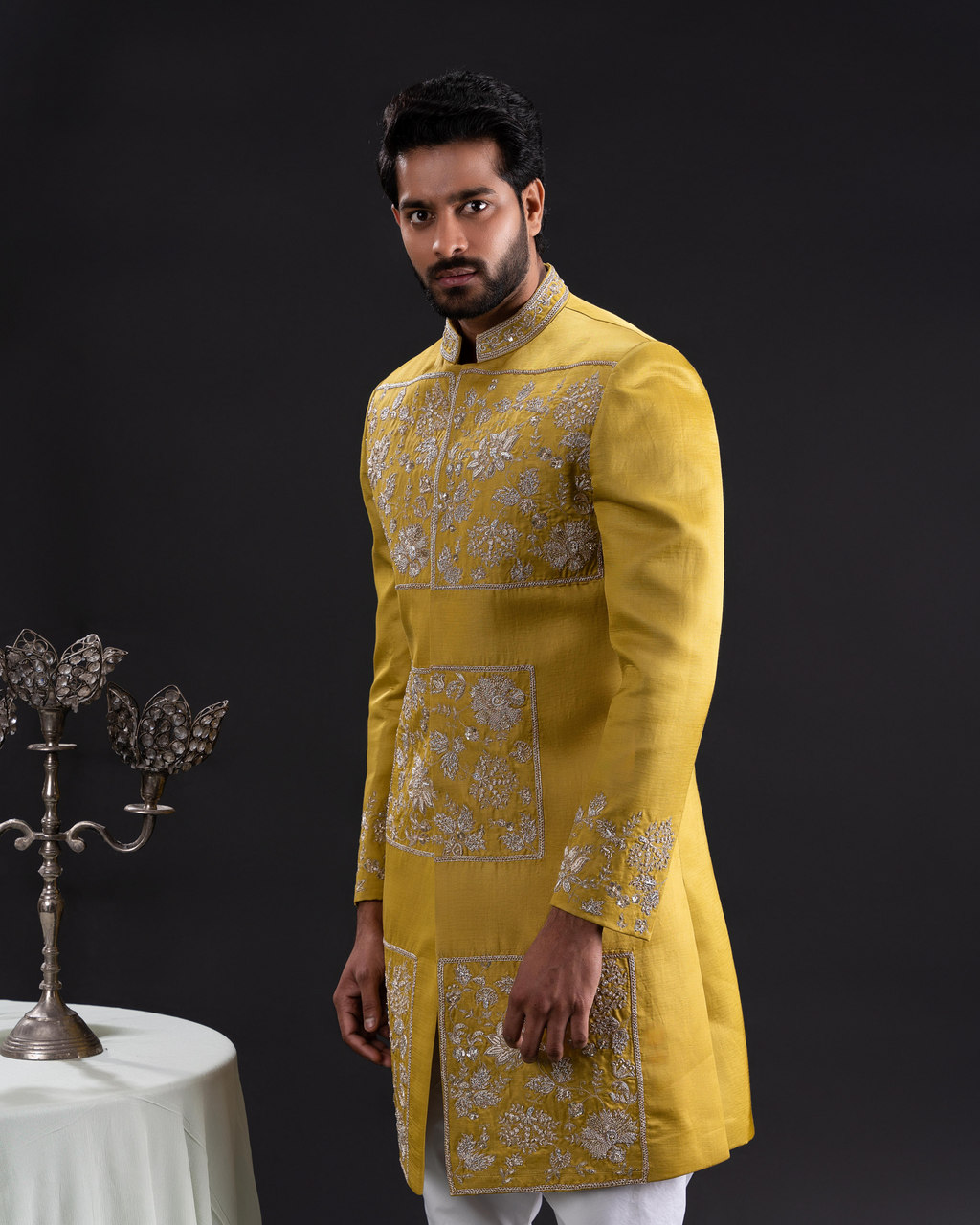 Frontal shot highlighting golden motifs on sherwani and structured fit.