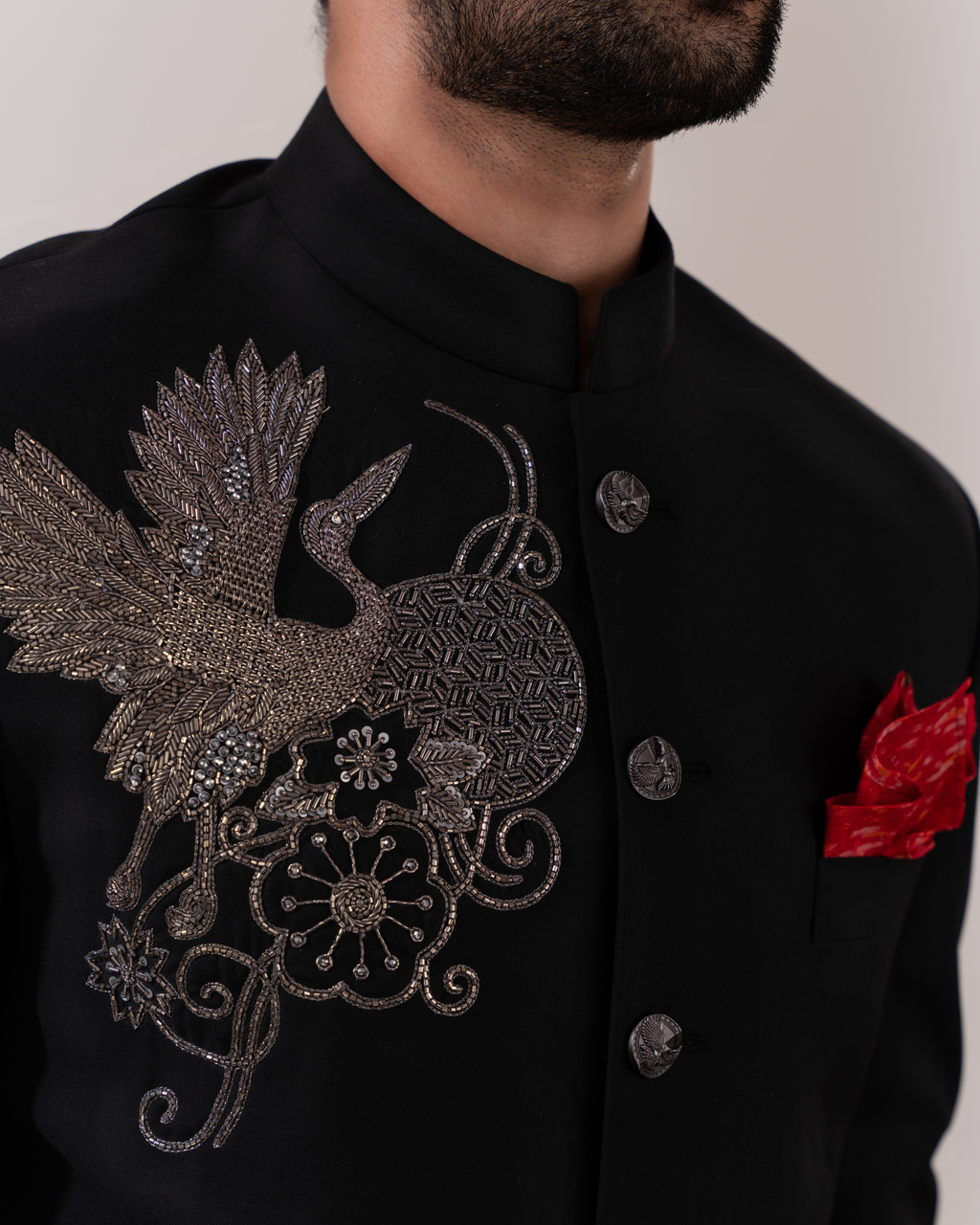 Black embroidered jacket with a bird design and red pocket square 