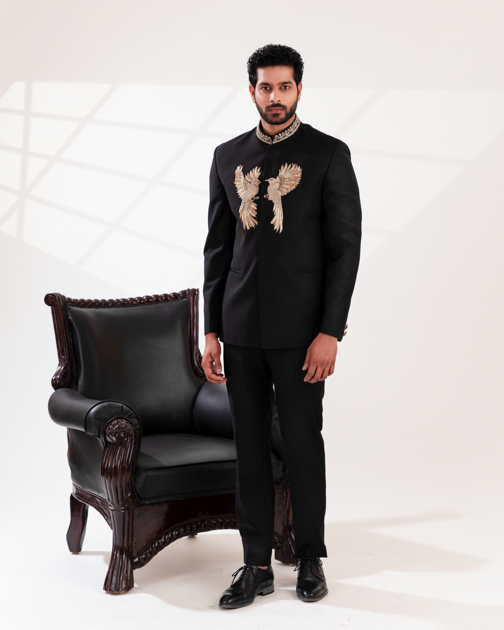 Front angle of black bandhgala showcasing gold embroidery and sharp silhouette.