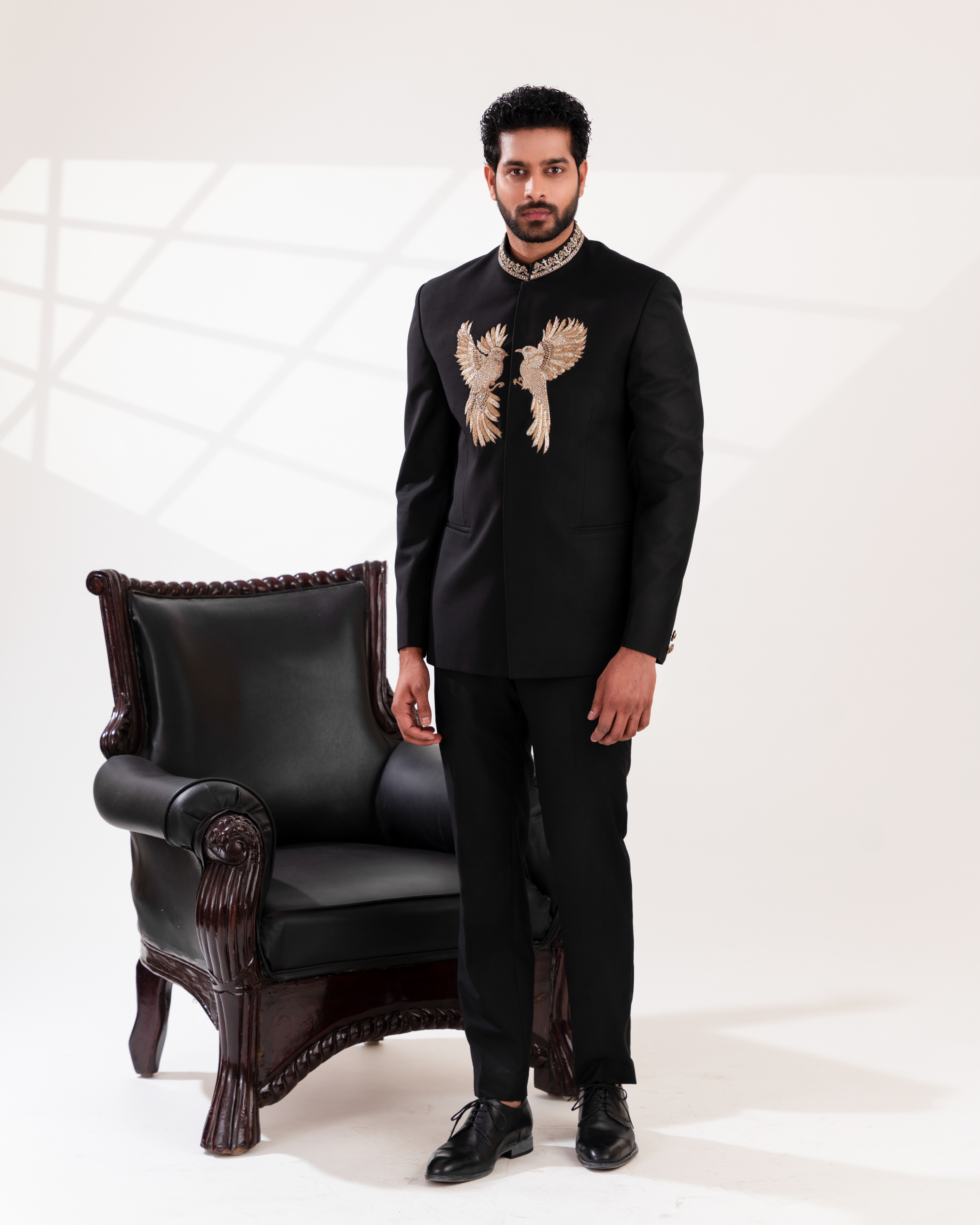 Front angle of black bandhgala showcasing gold embroidery and sharp silhouette.