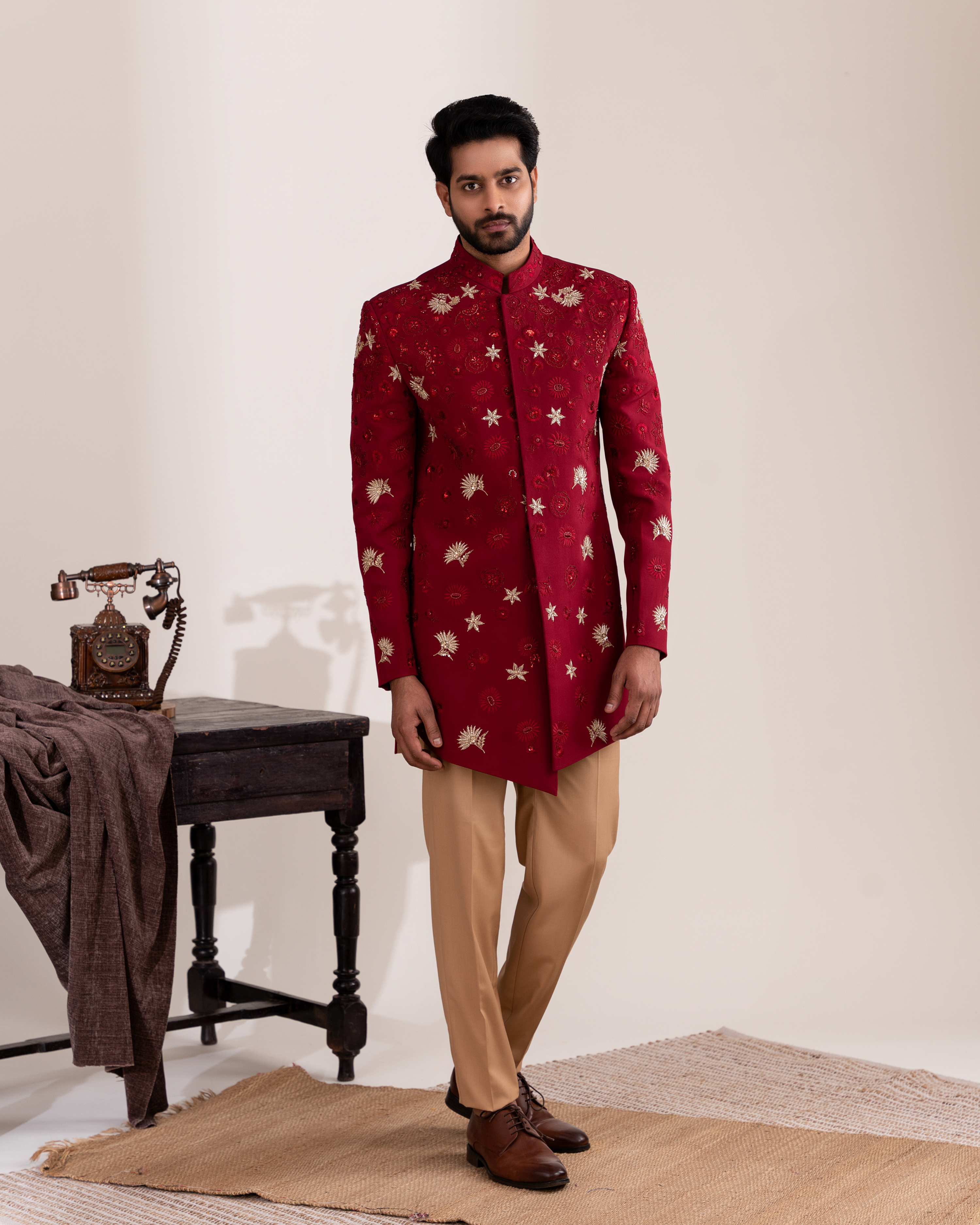 Man wearing a red embroidered sherwani with beige pants 