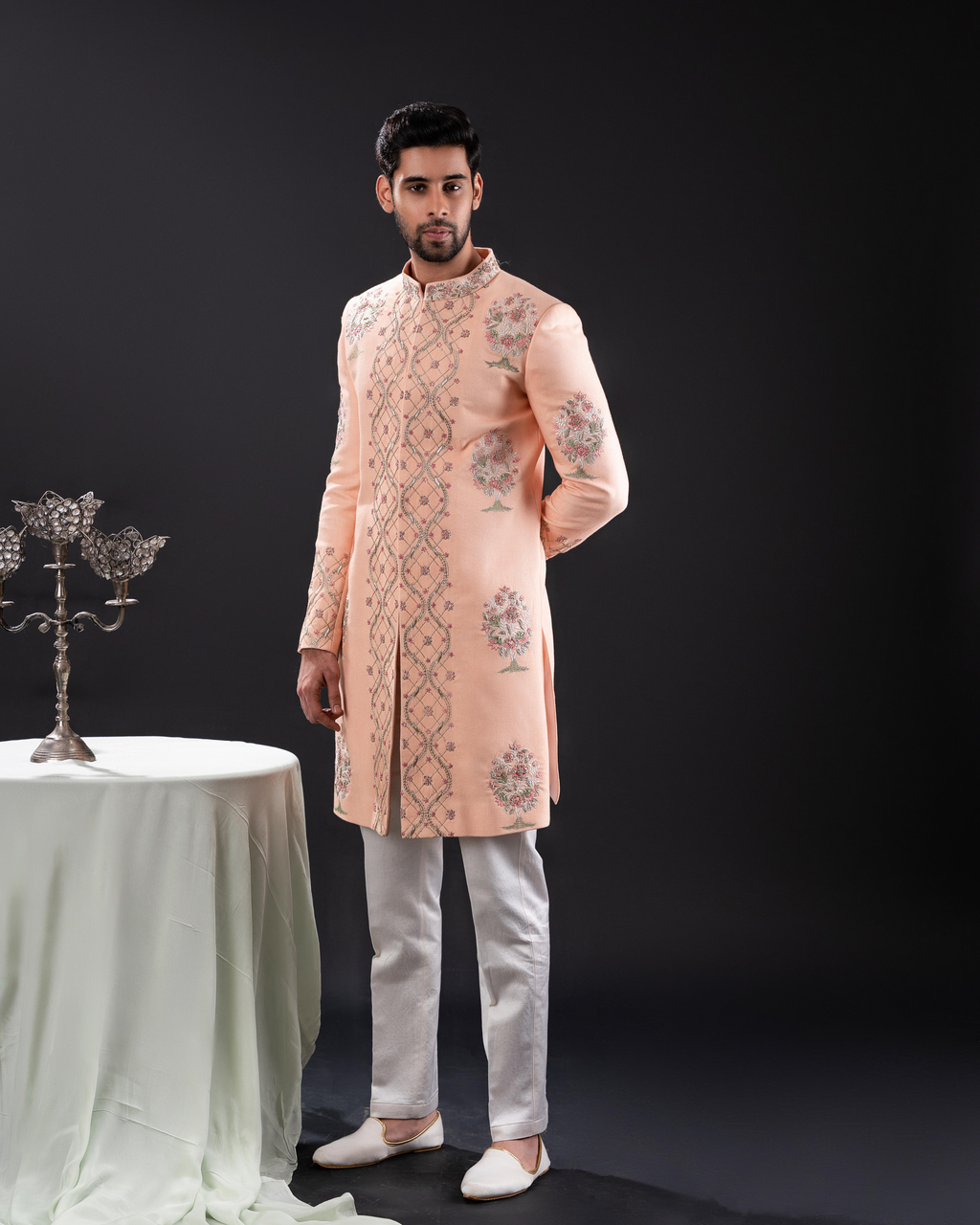 Front view of a peach sherwani with floral embroidery.
