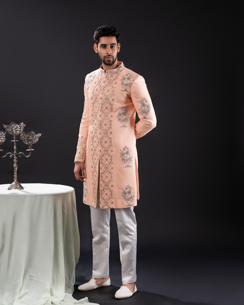 Front view of a peach sherwani with floral embroidery.