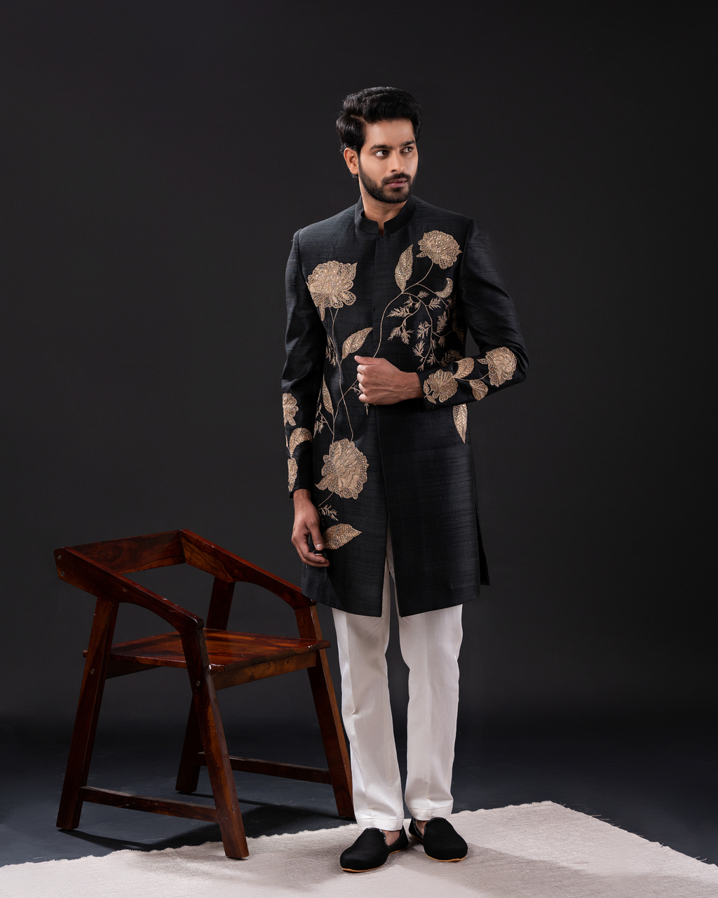Man wearing a black embroidered sherwani with white pants 