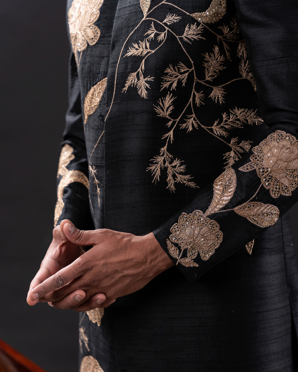 Close-up of golden floral embroidery on black sherwani