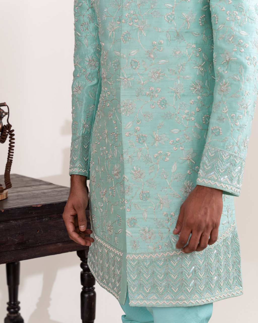 Closeup shot of embroidery on the hem of aqua sherwani 