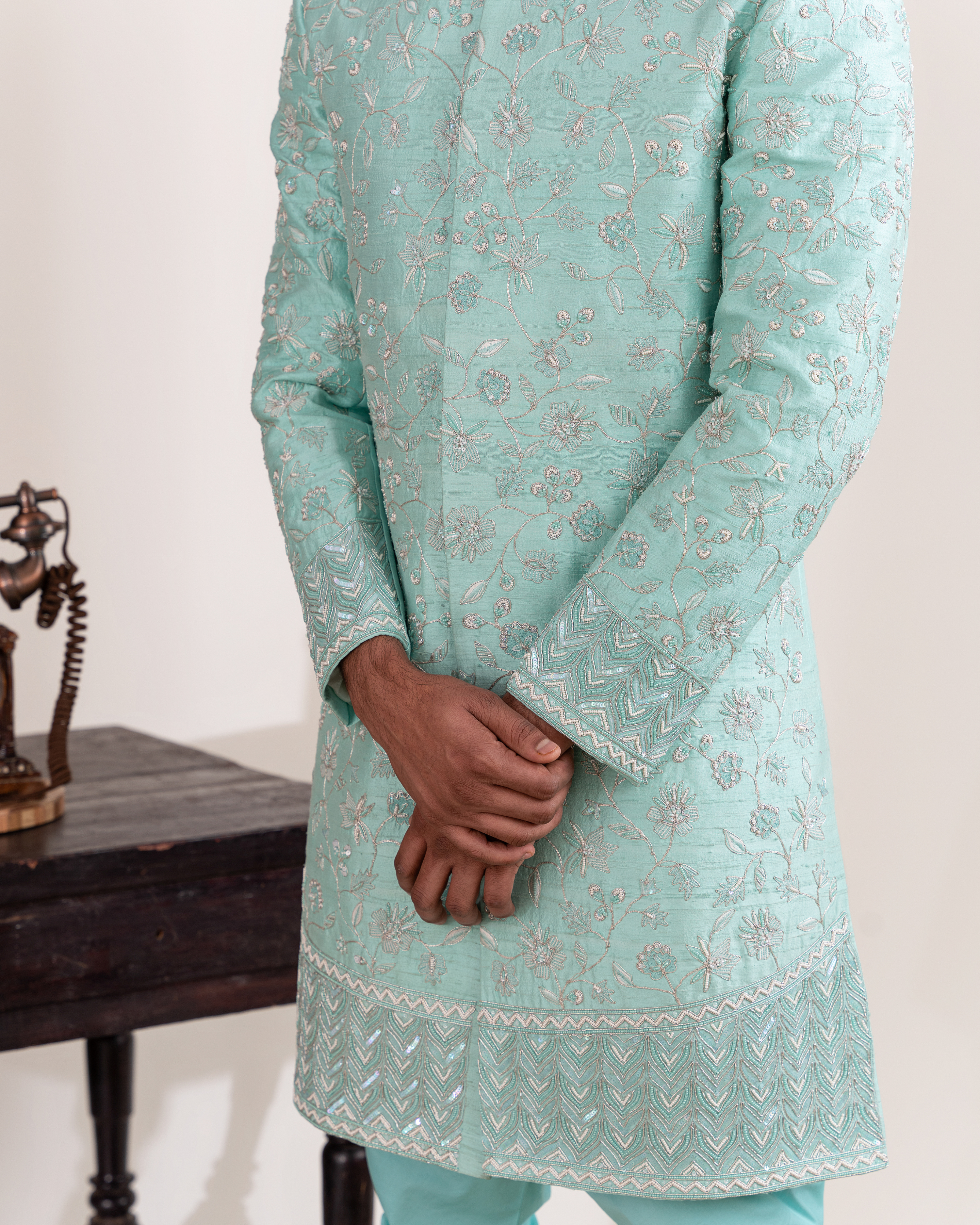 Close-up of floral embroidery on the aqua sherwani and sleeves