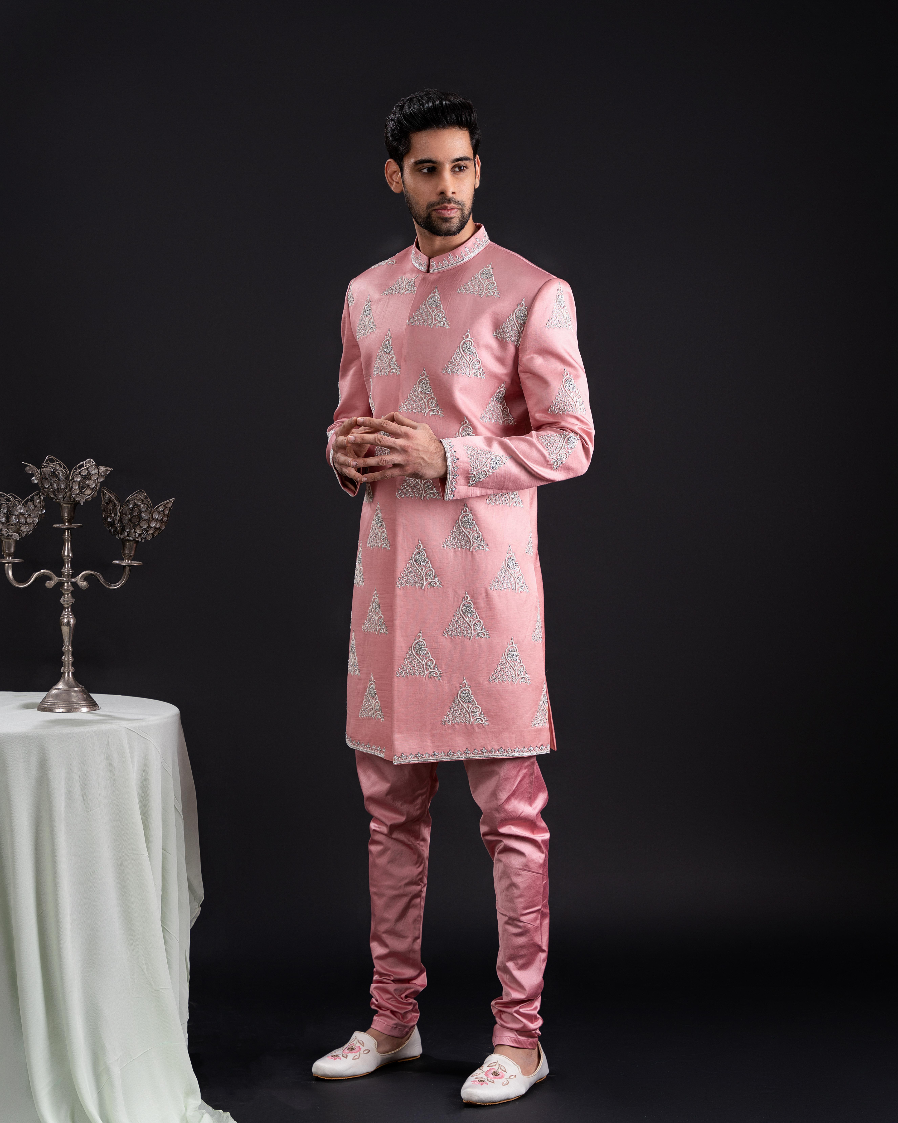 Front view of a salmon sherwani with pearl detailing and matching chudi pant